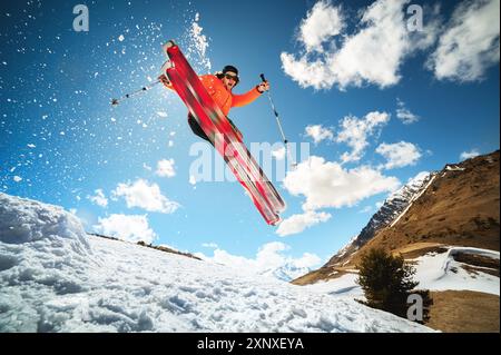 Sautez avec un tour dans le skieur athlète ozdou avec un kicker sur une journée ensoleillée du printemps ou de l'hiver. contre le ciel bleu et le soleil Banque D'Images