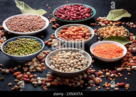 Assortiment de légumineuses sur fond noir. Lentilles, soja, pois chiches, haricots rouges, une vatiété des légumineuses Banque D'Images