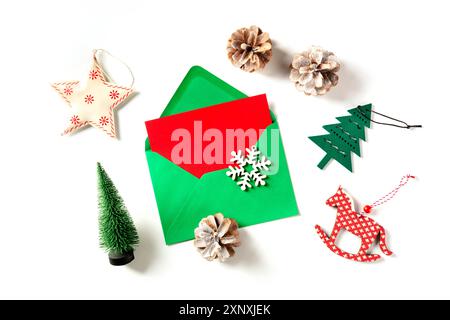 Une carte de vœux rouge de Noël dans une enveloppe verte, prise du haut sur un fond blanc avec des décorations du nouvel an et un lieu pour le texte Banque D'Images