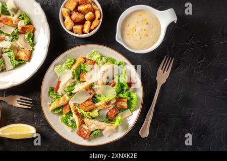 Salade César au poulet, prise d'en haut avec des croûtons et la vinaigrette classique, sur fond noir avec un espace pour le texte Banque D'Images