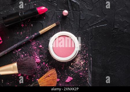 Pinceau à maquillage, fard à joues et rouge à lèvres, plan de dessus plat sur fond sombre avec espace de copie Banque D'Images