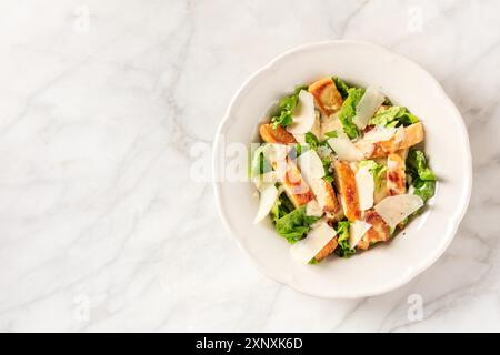 Salade César avec viande de poulet grillée, feuilles de romaine et parmesan, photographiée du haut avec espace copie Banque D'Images