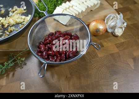 Haricots rouges et tofu, oignon et herbes, sources de protéines végétaliennes et ingrédients pour un plat sain comme trempette ou tartinade, table de cuisine en bois, espace de copie, Banque D'Images