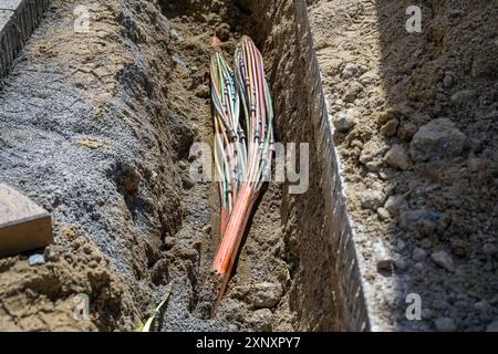 Câble souterrain avec plusieurs fibres optiques posées dans une tranchée dans le trottoir excavé, communication et concept d'infrastructure, espace de copie, sélectionnez Banque D'Images