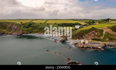 Paysage panoramique aérien du club de plongée en haute mer Porthoustock en Cornouailles avec littoral rocheux et plage de galets abritée sur la péninsule de Lizard Banque D'Images