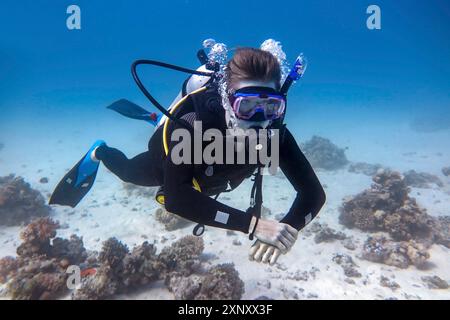 Jeune plongeur caucasien flottant sous l'eau dans la mer bleue Banque D'Images
