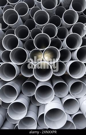 Tubes en PVC gris tuyaux en plastique empilés dans des rangées avec un shinning léger à travers Banque D'Images