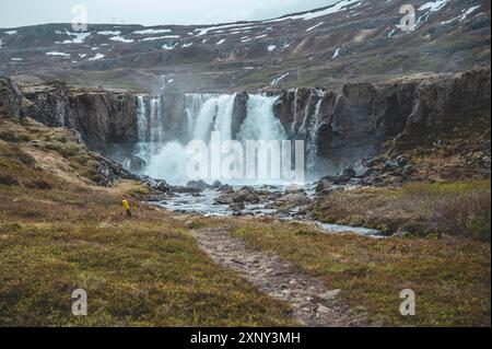 Belle cascade à Seydisfjordur, Islande avec des montagnes de neige en arrière-plan Banque D'Images