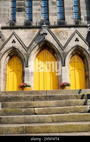 Trois portes jaune vif à l'avant d'une église Banque D'Images