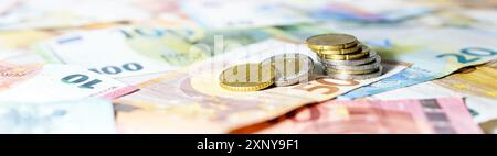 Pile de pièces sur les billets en euros en format panoramique large, concept d'en-tête de site Web pour les affaires, la finance ou l'inflation, espace de copie, focus sélectionné Banque D'Images