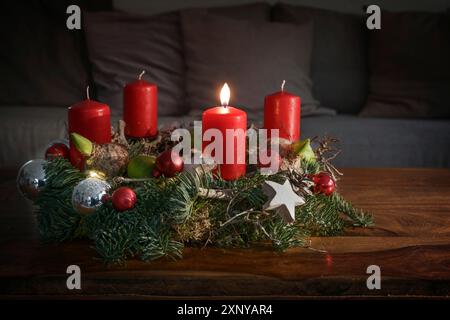 Couronne de l'Avent avec une bougie rouge allumée et décoration de Noël sur une table en bois devant le canapé, décoration festive pour la maison pour le premier dimanche Banque D'Images