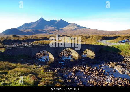 Un vieux pont de pierre enjambe une rivière devant un paysage montagneux sous un ciel bleu clair, octobre, Slichigan, Cullins, Hébrides, île de Skye Banque D'Images