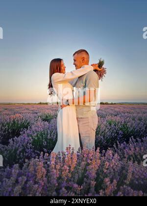 Couple serrant ensemble sur une date dans le champ de fleurs de lavande. Scène d'été idyllique, concept d'amour et de romance Banque D'Images