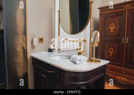 Salle de bains luxueuse avec vanité en bois foncé et accents dorés dans l'hôtel de luxe Banque D'Images