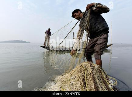 Pêcheur nettoyant les plastiques et autres matériaux de leur filet de pêche après avoir pêché dans la rivière Brahmapoutre à Guwahati, Assam, Inde, mardi 19 Banque D'Images