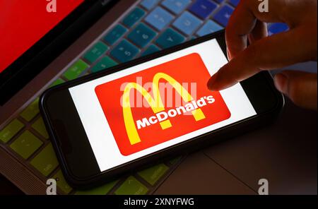 Dans cette illustration photo, le logo McDonald's est affiché sur un smartphone avec un arrière-plan d'écran d'ordinateur portable. Les ventes de McDonald's chutent pour la première fois dans le monde Banque D'Images