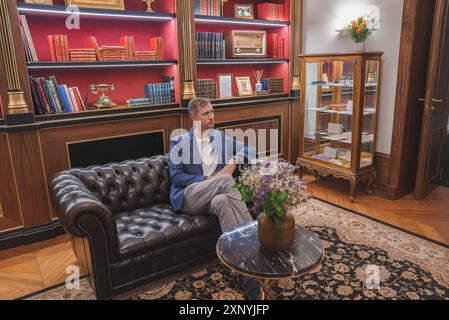 Intérieur luxueux de l'hôtel avec homme sur le canapé Chesterfield et élégante bibliothèque Banque D'Images