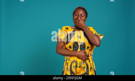 Femme se sentant extrêmement fatiguée et bâillant sur fond bleu, jeune adulte surchargé de travailler avec la privation de sommeil en studio. Épuisé adulte fatigué avec burnout. Caméra B. Banque D'Images