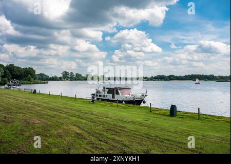 Linden, Gueldre, pays-Bas, 11 juillet 2024 - bateau de plaisance sur les rives vertes de la Maas Banque D'Images