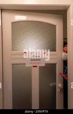 Image symbolique quarantaine domestique, l'homme est en isolement à la maison en raison d'une infection corona suspectée, signe d'avertissement pour les visiteurs sur la porte d'entrée Banque D'Images