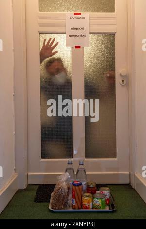 Image symbolique quarantaine domestique, l'homme est en isolement à la maison en raison d'une infection corona suspectée, signe d'avertissement pour les visiteurs sur la porte d'entrée Banque D'Images