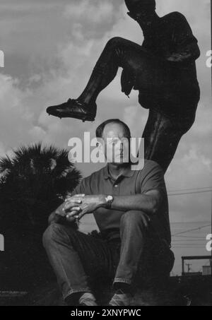 Le lanceur du Hall of Fame du baseball NOLAN RYAN pose dans le centre-ville d'Alvin, Texas, à côté d'une statue de lui-même en train de lancer. La statue en bronze a été réalisée par le sculpteur Jack Bryant et dévoilée en 1992 devant l'hôtel de ville d'Alvin. Ceci a été photographié pour le programme All-Star 1995. Original en couleur ©Bob Daemmrich Banque D'Images