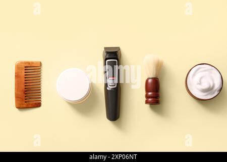 Tondeuse moderne, crème à raser et brosse à cheveux sur fond jaune Banque D'Images