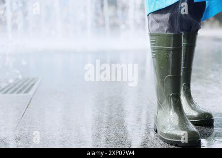 Personne portant des bottes en caoutchouc pendant de fortes pluies à l'extérieur, gros plan Banque D'Images