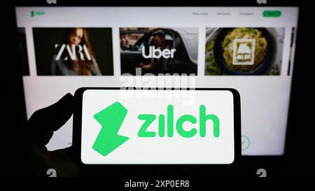 Stuttgart, Allemagne, 03 30 2022 : personne tenant un smartphone avec le logo de la fintech Zilch Technology Limited (PayZilch) sur l'écran devant le site. Banque D'Images