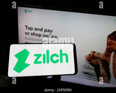 Stuttgart, Allemagne, 03 30 2022 : personne tenant un téléphone portable avec le logo de la fintech Zilch Technology Limited (PayZilch) sur l'écran devant l'entreprise Banque D'Images