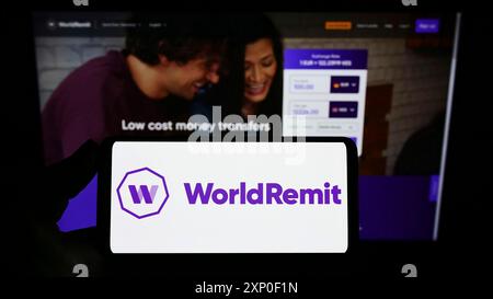 Stuttgart, Allemagne, 03-29-2022, personne tenant un smartphone avec le logo de la société de paiement britannique WorldRemit Limited sur l'écran devant le site Web. Banque D'Images