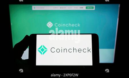 Stuttgart, Allemagne, 03-29-2022, personne tenant un smartphone avec le logo de la société japonaise de crypto-monnaie Coincheck Inc. sur l'écran devant le site Web. Banque D'Images