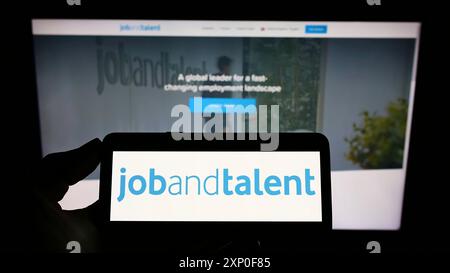 Stuttgart, Allemagne, 03-29-2022, personne tenant un téléphone portable avec le logo de la société Jobs and talent SL (Jobandtalent) sur l'écran devant l'entreprise Banque D'Images