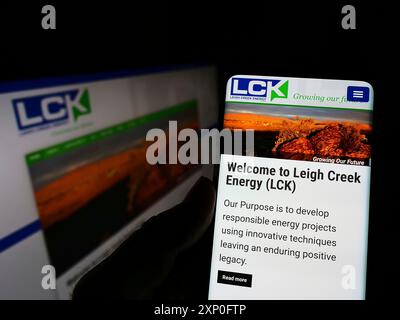 Stuttgart, Allemagne, 03-06-2022 : personne tenant un smartphone avec le site Web de la société australienne Leigh Creek Energy Limited sur l'écran avec moniteur. Mise au point Banque D'Images