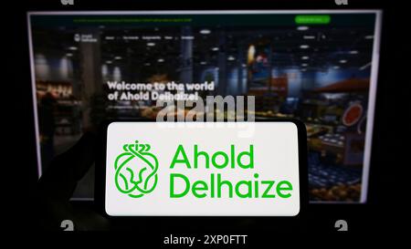 Stuttgart, Allemagne, 03-06-2022 : personne tenant un smartphone avec le logo de la société néerlandaise Koninklijke Ahold Delhaize N.V. sur l'écran devant le site. Banque D'Images