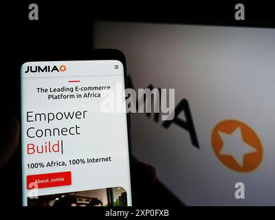 Stuttgart, Allemagne, 03-06-2022 : personne tenant un téléphone portable avec le site web de la société nigériane Jumia technologies sur l'écran devant le logo de l'entreprise. Banque D'Images