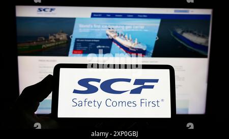 Stuttgart, Allemagne, 05-08-2022 : personne tenant un smartphone avec le logo de la compagnie maritime russe Sovcomflot (SCF) sur l'écran devant le site. Mise au point Banque D'Images