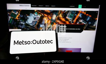 Stuttgart, Allemagne, 02-26-2022, personne tenant un smartphone avec le logo de la société finlandaise Metso Outotec Oyj sur l'écran devant le site Web. Banque D'Images