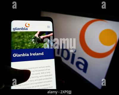 Stuttgart, Allemagne, 01-29-2022, personne tenant un téléphone portable avec la page web de la société irlandaise de nutrition Glanbia plc sur l'écran devant le logo. Concentrez-vous sur Banque D'Images