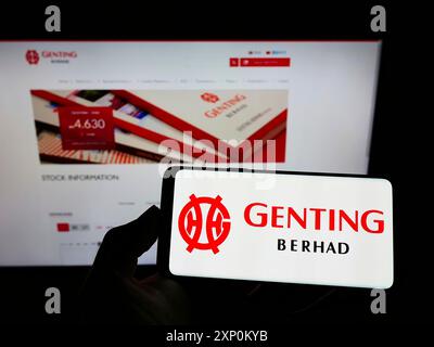 Stuttgart, Allemagne, 01-15-2022 : personne tenant un smartphone avec le logo du conglomérat malaisien Genting Group sur l'écran devant le site Web. Concentrez-vous sur Banque D'Images