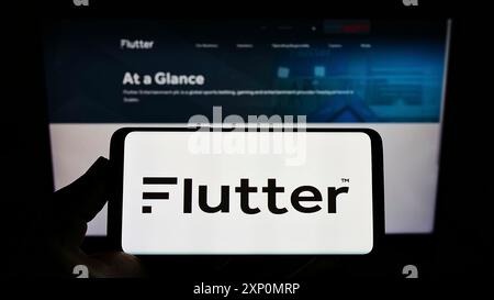 Stuttgart, Allemagne, 01-06-2022 : personne tenant un téléphone portable avec le logo de la société irlandaise Flutter Entertainment plc sur l'écran devant le web Banque D'Images