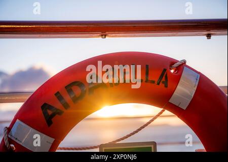 Gros plan orange AIDA Bella bouée de sauvetage au coucher du soleil, rayon du soleil Banque D'Images