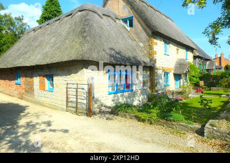 Maison de village Gaydon maisons de rue cottage chalets pub bar toit chaume chaume jolies fleurs plantes plante fleur style ancien paniers suspendus panier Banque D'Images