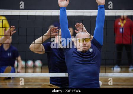 Jeu de volley-ball assis. Vétérans pratiquant un sport d'équipe adaptatif pendant la compétition Air Force Trials. Kiev - 12 décembre 2023 Banque D'Images