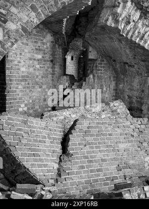 Image en noir et blanc d'un mur de briques en ruine antique, montrant la pourriture et l'architecture historique Banque D'Images