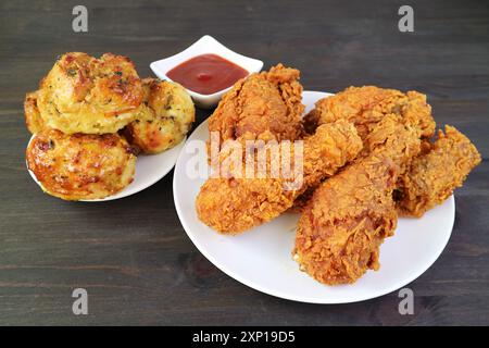 Assiette de délicieux poulets frits avec biscuits aromatiques aux herbes servies sur une table en bois Banque D'Images
