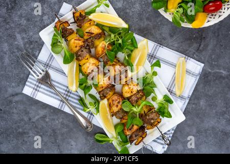 Agneau grillé, poivrons jaunes et brochettes de pommes de terre avec salade de feuilles vertes Banque D'Images