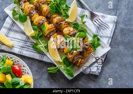 Agneau grillé, poivrons jaunes et brochettes de pommes de terre avec salade de feuilles vertes Banque D'Images