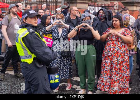 Liverpool, Royaume-Uni. 02 AOÛT 2024. Les manifestants créent des cœurs avec leurs mains sur le côté SUTR de la route alors que les manifestants s'identifient comme étant de droite, ainsi que les membres du SUTR et des organisations de gauche rassemblés sur les côtés opposés de la route à l'extérieur de la mosquée Abdullah Quilliam, l'une des premières mosquées d'Angleterre, dans un contexte d'émeutes à travers le pays suite à un incident à Southport. En dehors de quelques cris et des manifestants qui traversent brièvement les côtés, aucun problème n'a été observé. Crédit Milo Chandler/Alamy Live News Banque D'Images