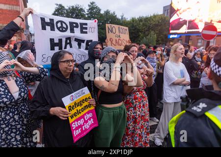 Liverpool, Royaume-Uni. 02 AOÛT 2024. Les manifestants créent des cœurs avec leurs mains sur le côté SUTR de la route alors que les manifestants s'identifient comme étant de droite, ainsi que les membres du SUTR et des organisations de gauche rassemblés sur les côtés opposés de la route à l'extérieur de la mosquée Abdullah Quilliam, l'une des premières mosquées d'Angleterre, dans un contexte d'émeutes à travers le pays suite à un incident à Southport. En dehors de quelques cris et des manifestants qui traversent brièvement les côtés, aucun problème n'a été observé. Crédit Milo Chandler/Alamy Live News Banque D'Images